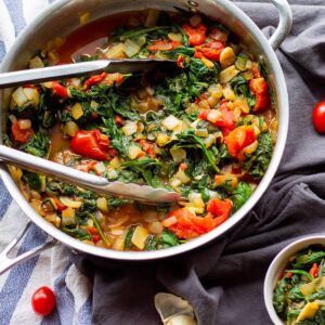 cooked spinach in metal pan with tongs