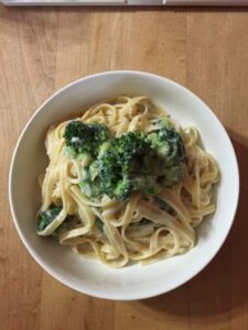 creamy cauliflower alfredo sauce with pasta in a bowl with broccoli on top