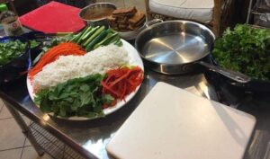 veggies and rice noodles on a plate next to tofu and a pan