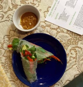 spicy peanut sauce in bowl next to plate of spring rolls