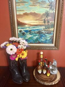 cowboy boots with flowers next to painting of a beach