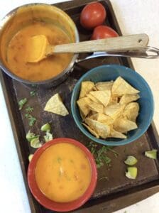 vegan queso with chips on a tray