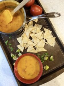 chips on a tray next to a bowl of vegan queso