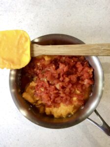 cheese sauce and diced tomato in a pot