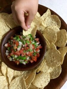 fresh salsa in a wooden bowl surrounded by tortilla chips