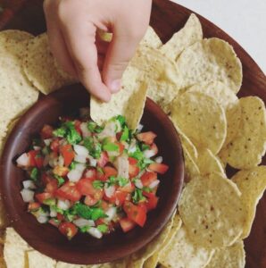 fresh salsa in a wooden bowl surrounded by tortilla chips