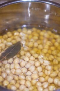 cooked chickpeas with bay leaf floating inside Instant Pot
