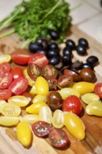 sliced tomatoes, olives and parsley on cutting board