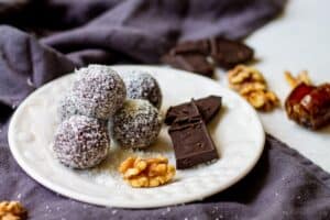 coconut covered chocolate date balls with chocolate and walnuts on plate