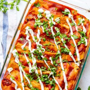 pan of enchiladas with sour cream and cilantro