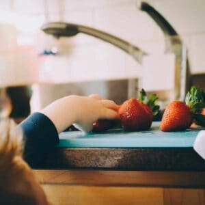 little boy reaching for strawberries