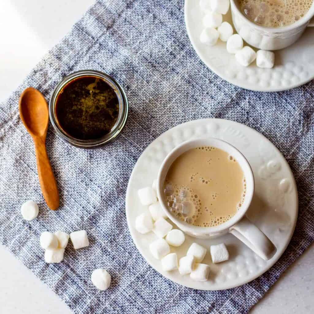 mugs of pumpkin spice steamers with marshmallows and pumpkin spice simple syrup on side