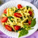pasta dish in white bowl, garnished by basil