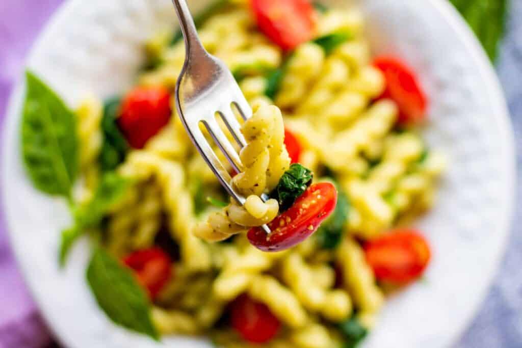 closeup of pesto pasta on fork
