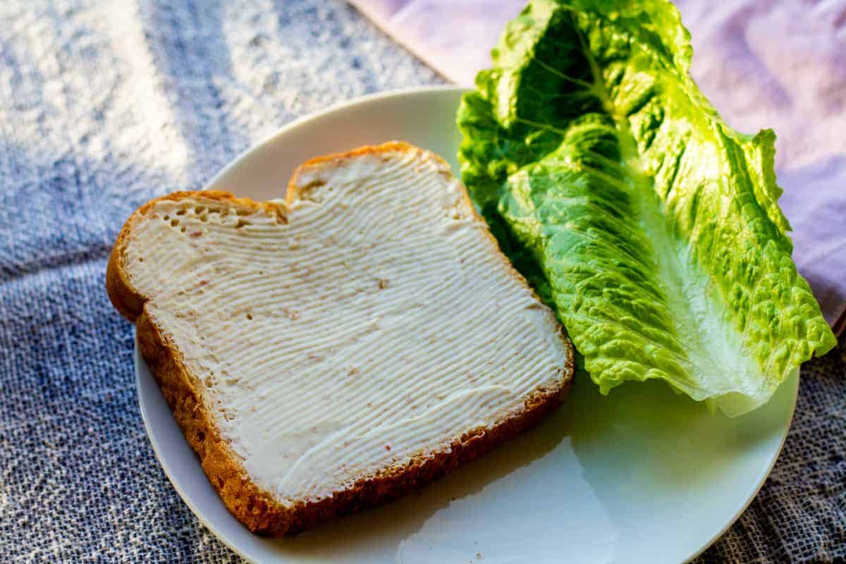 piece of bread with egg free mayo on it with lettuce on a plate