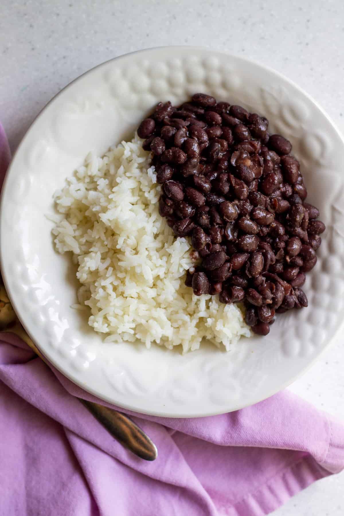 cooked black beans with cooked white rice in white bowl