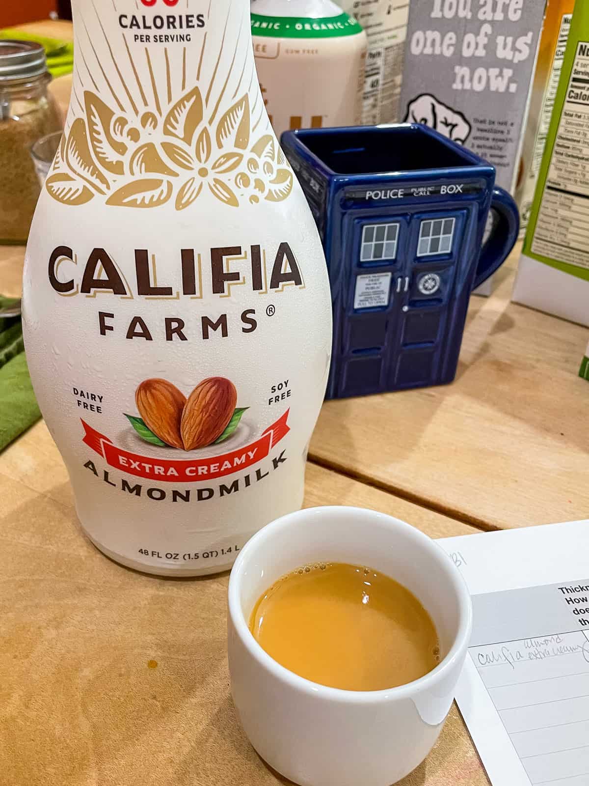 Califia Farms Extra Creamy Almondmilk with black milk tea in front in cup