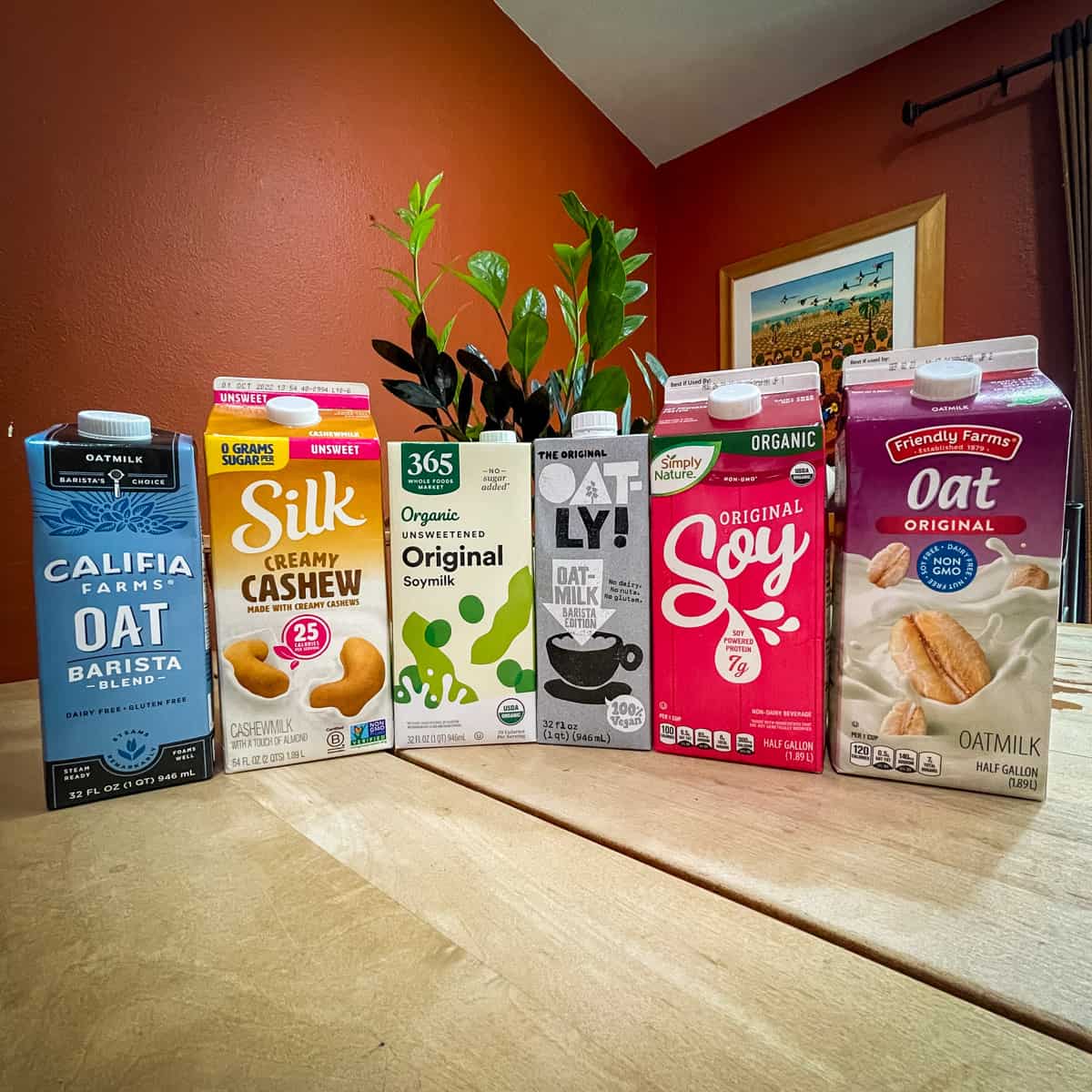 Six different vegan milks lined up, oat milk, cashew milk, soymilk