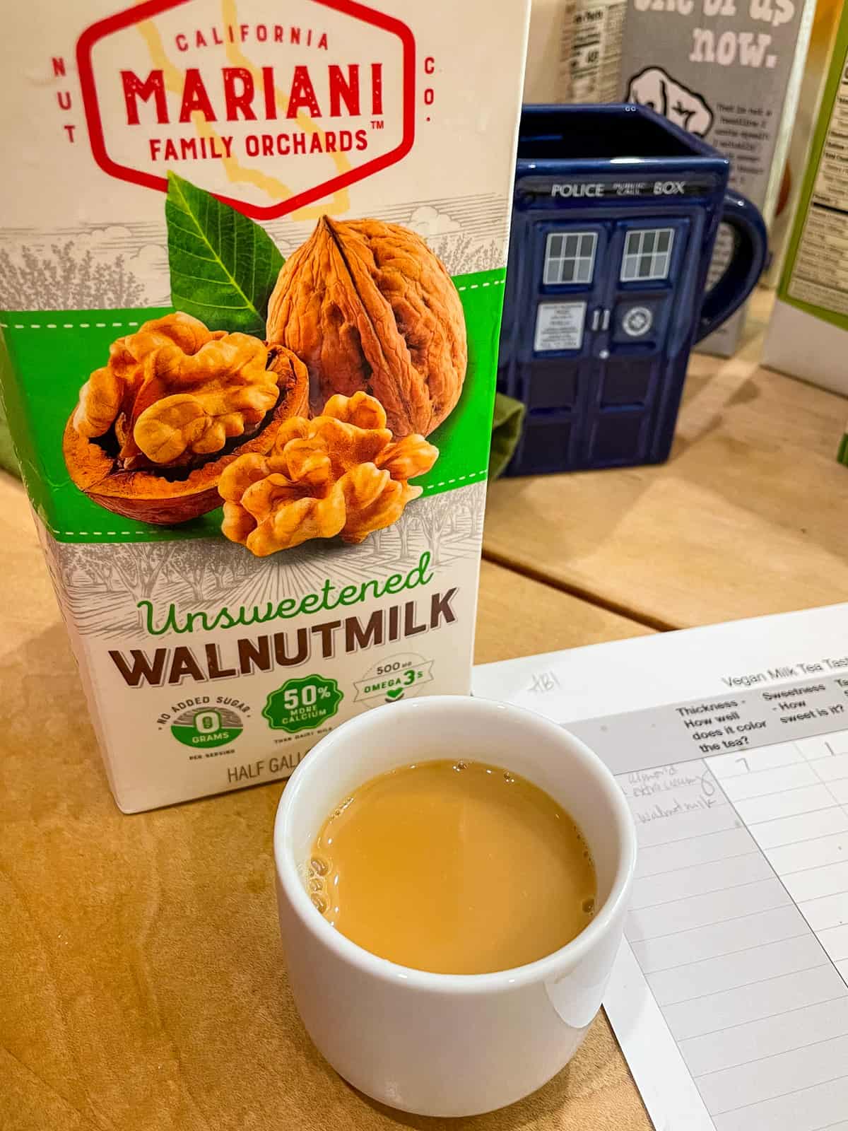 carton of mariani walnutmilk with cup of black yorkshire tea with milk in it