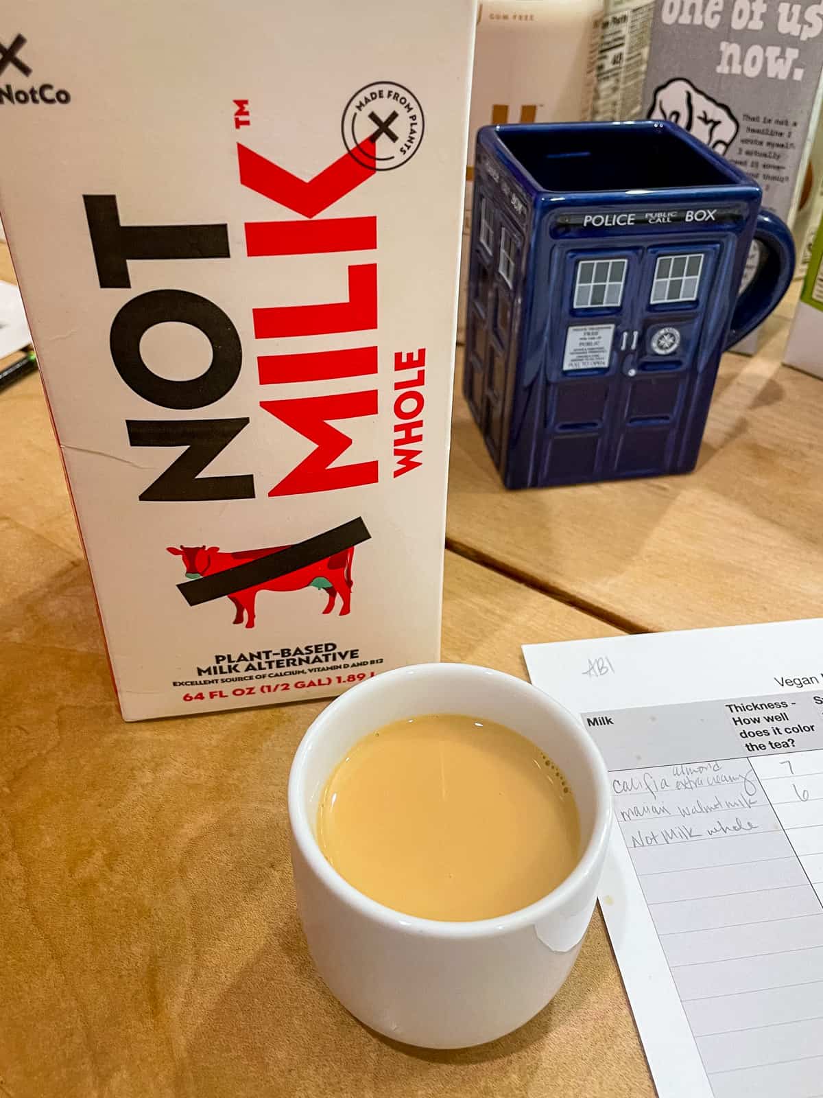 carton of not milk whole with cup of black tea in front