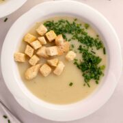pureed potato leak soup with croutons and chives on top