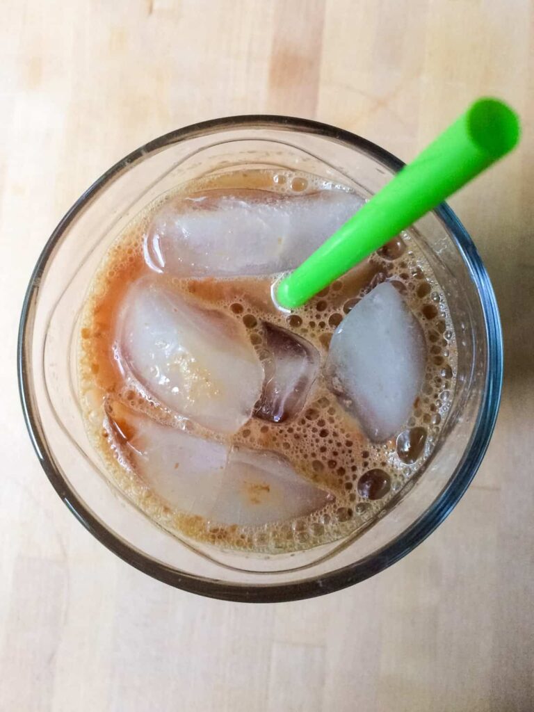 iced chai tea latte in glass with green straw