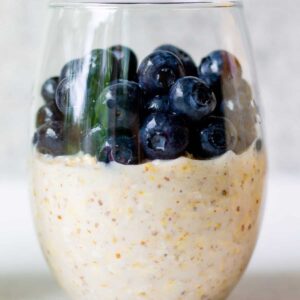 glass with vegan overnight oats and fresh blueberries on top