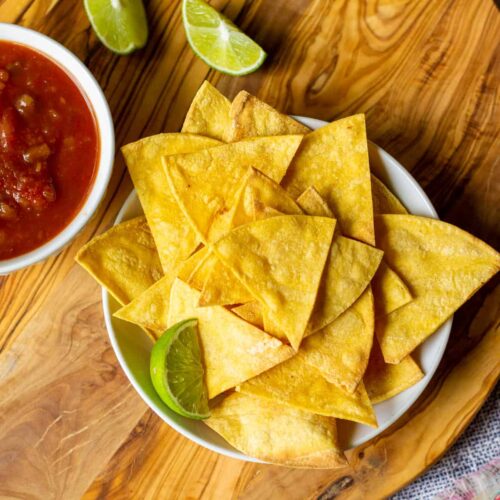 bowl of chips with salsa and limes