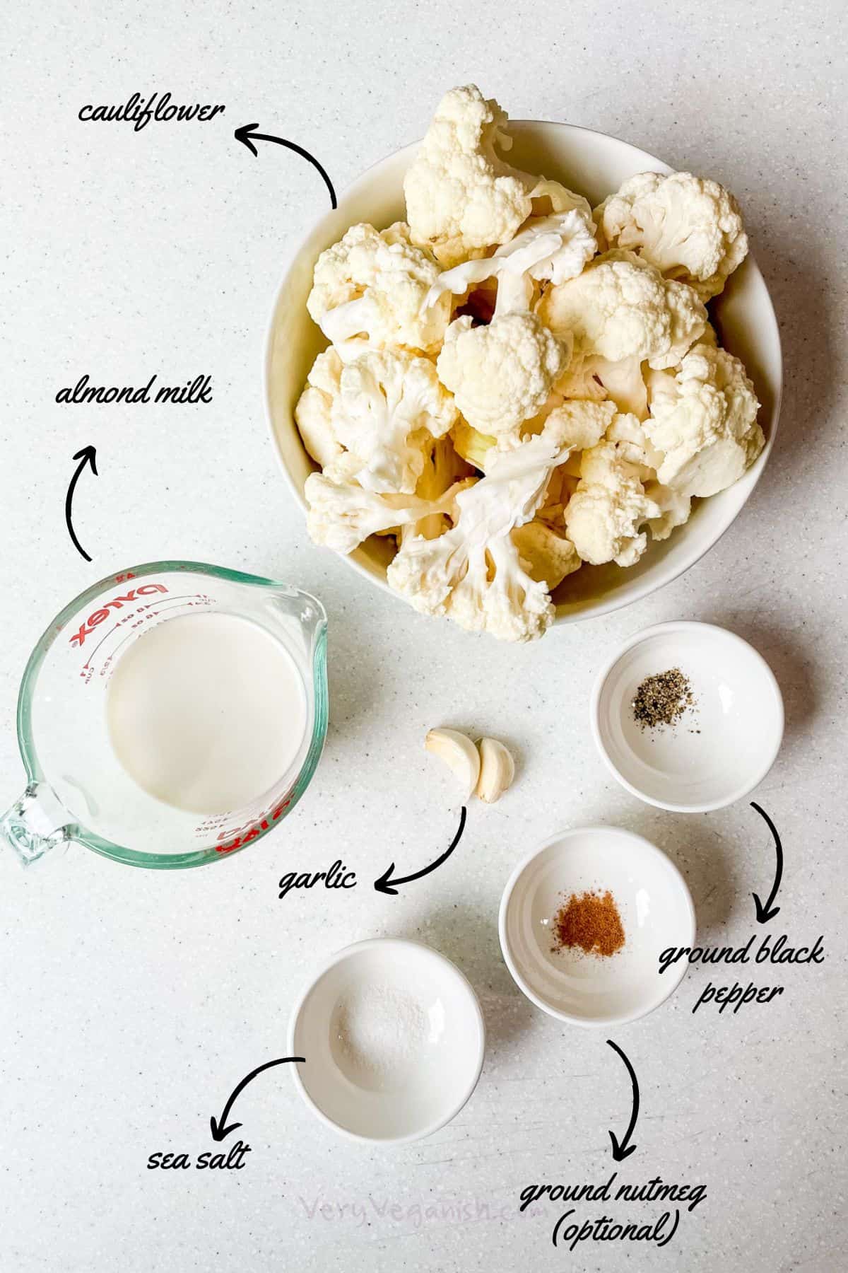 ingredients on counter: cauliflower florets, almond milk, ground black pepper, sea salt, garlic, ground nutmeg optional