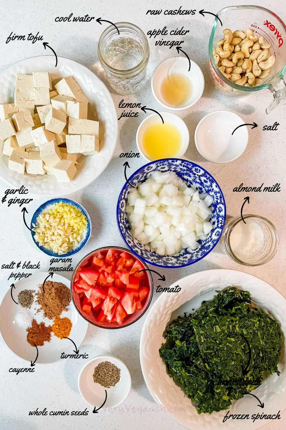 ingredients for vegan saag palak paneer with tofu: tofu, spinach, onion, tomato, garlic, ginger, cashew sour cream, garam masala, turmeric, cayenne, whole cumin seeds, salt and pepper