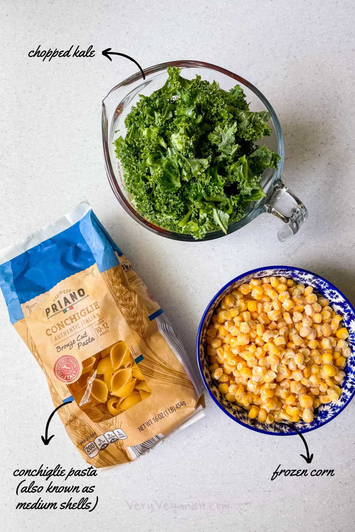 ingredients on counter: conchiglie medium shells pasta, chopped curly kale and frozen corn kernels