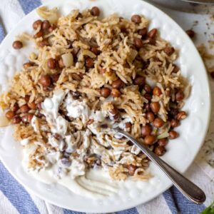 white plate full of rice and pigeon peas with cashew sour cream on side