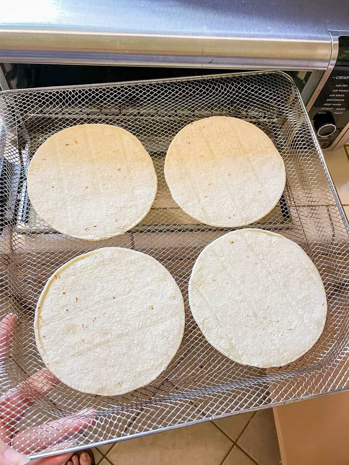four corn tortillas on air fryer basket
