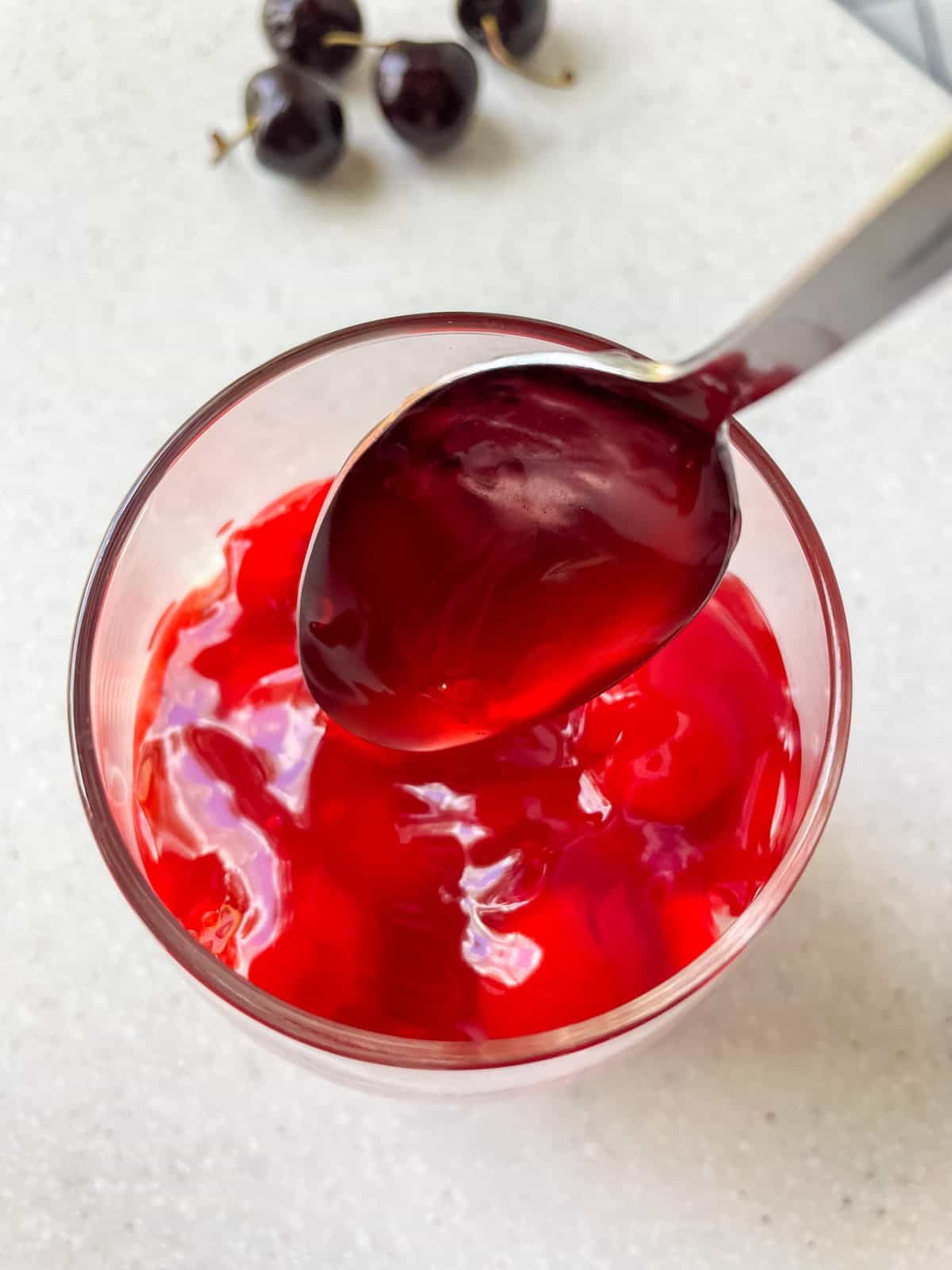 carefully spooning cherry pie filling into glass