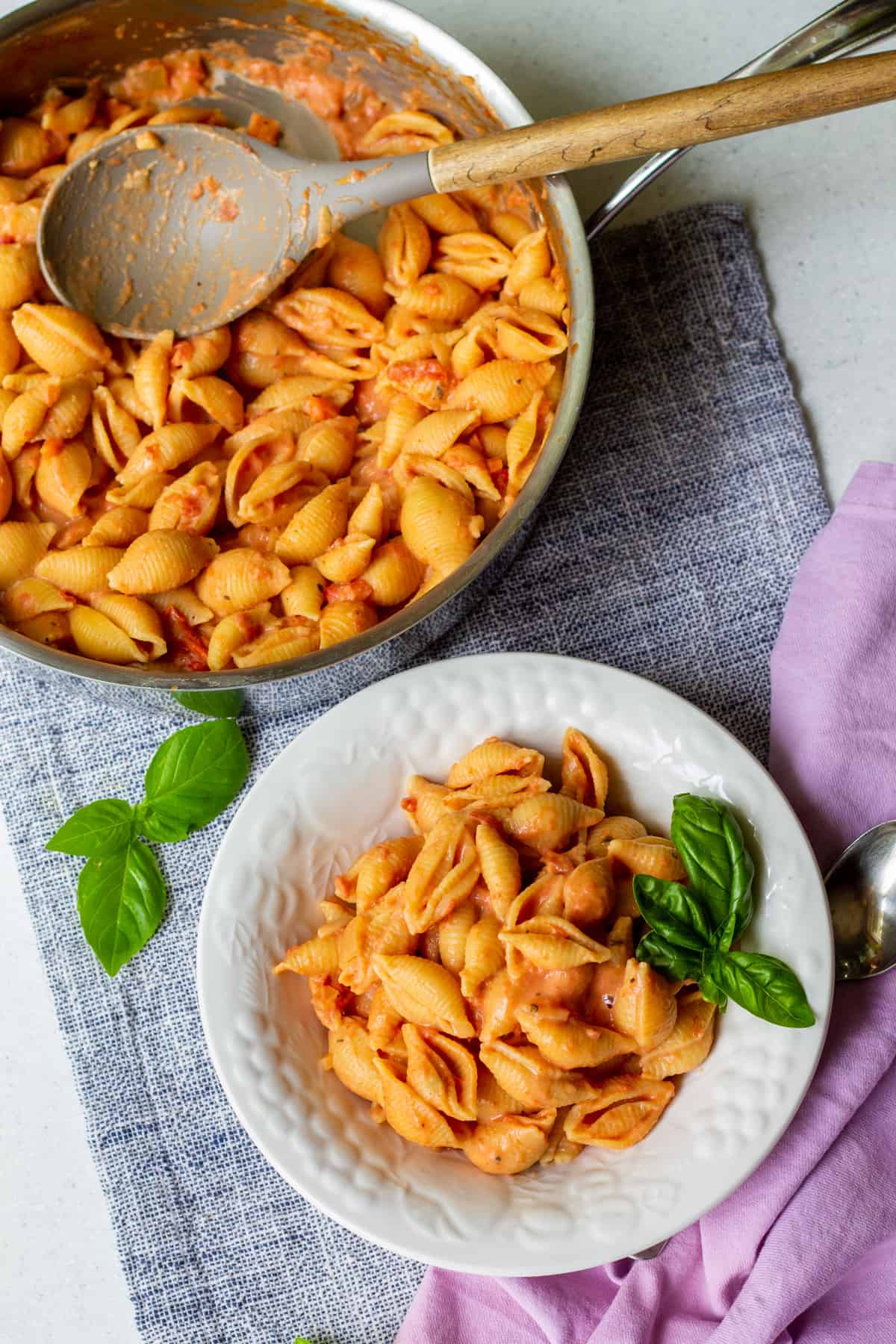 creamy tomato shell pasta in pan with fresh basil