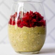 pretty glass with matcha overnight oats and thawed, frozen raspberries on top