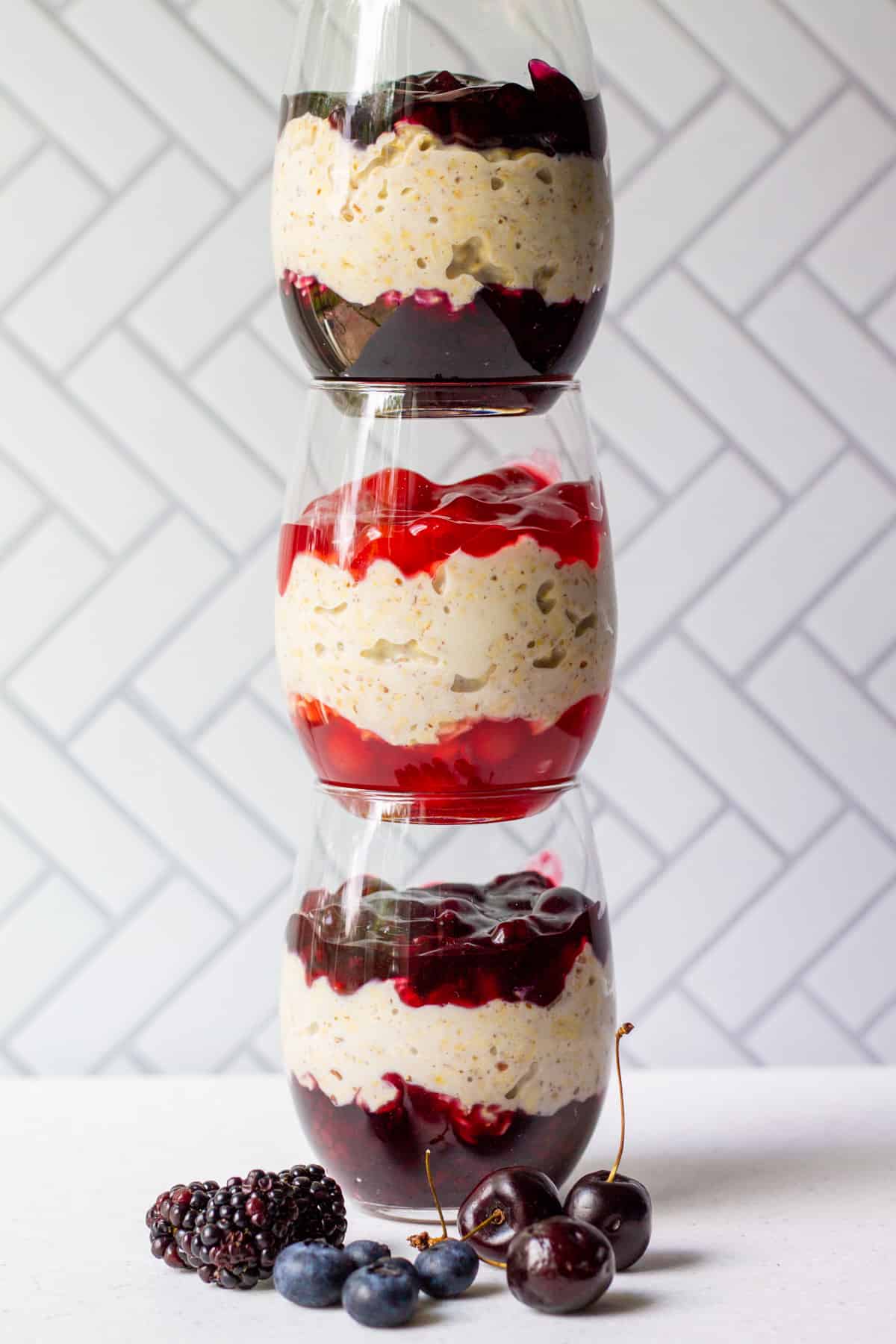 three glasses of different flavor pie overnight oats with canned pie filling: blackberry, cherry and blueberry
