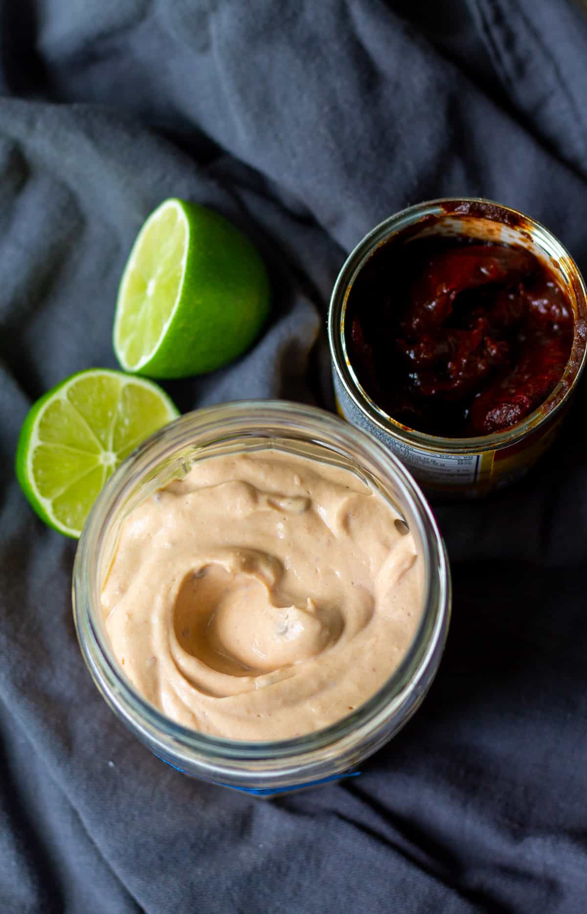 chipotle mayo in open jar, next to can of chipotle peppers in adobo sauce, cut limes