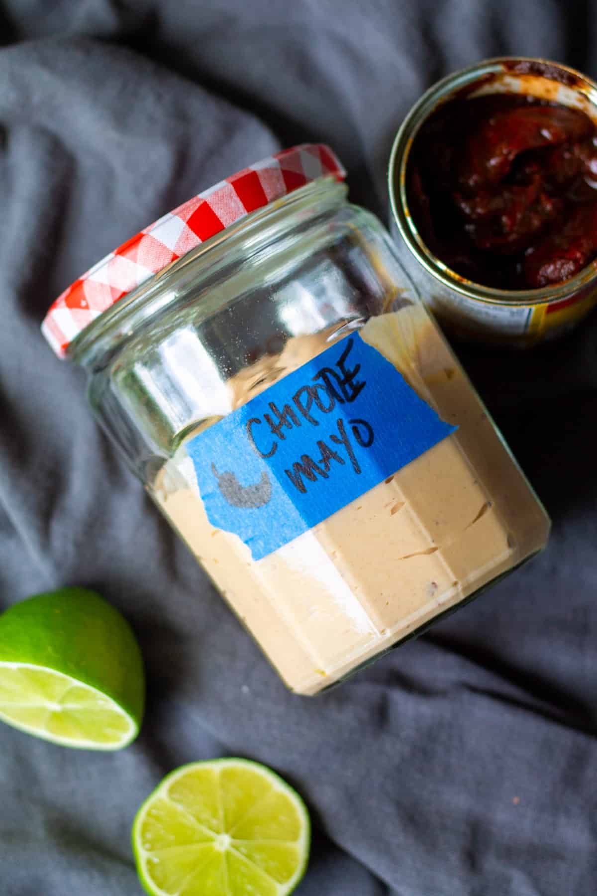 chipotle mayo in jar with red and white lid, next to can of chipotle peppers in adobo sauce, cut limes