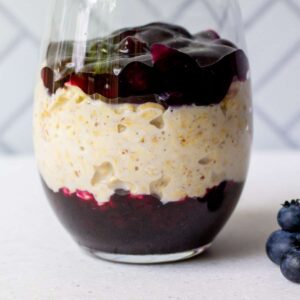 glass full of premium blueberry pie filling and overnight oats with fresh blueberries on side