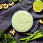 cilantro lime jalapeno crema in small bowl with lime, cashews and jalapeno on the side