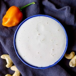 habanero cashew cream in small bowl with raw cashews and habanero chile on side