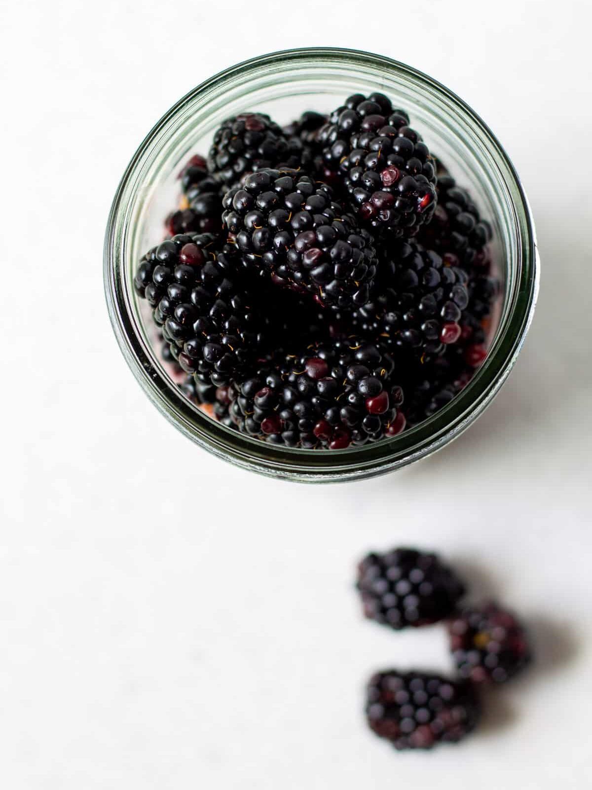 top view blackberry jam overnight oats with fresh blackberries on top in a mason jar