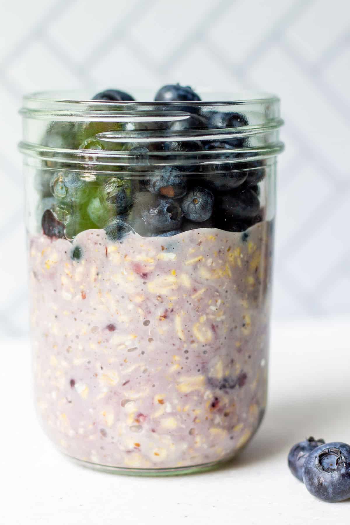 mason jar with blueberry flavored oats and fresh blueberries on top