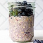 mason jar with blueberry flavored oats and fresh blueberries on top