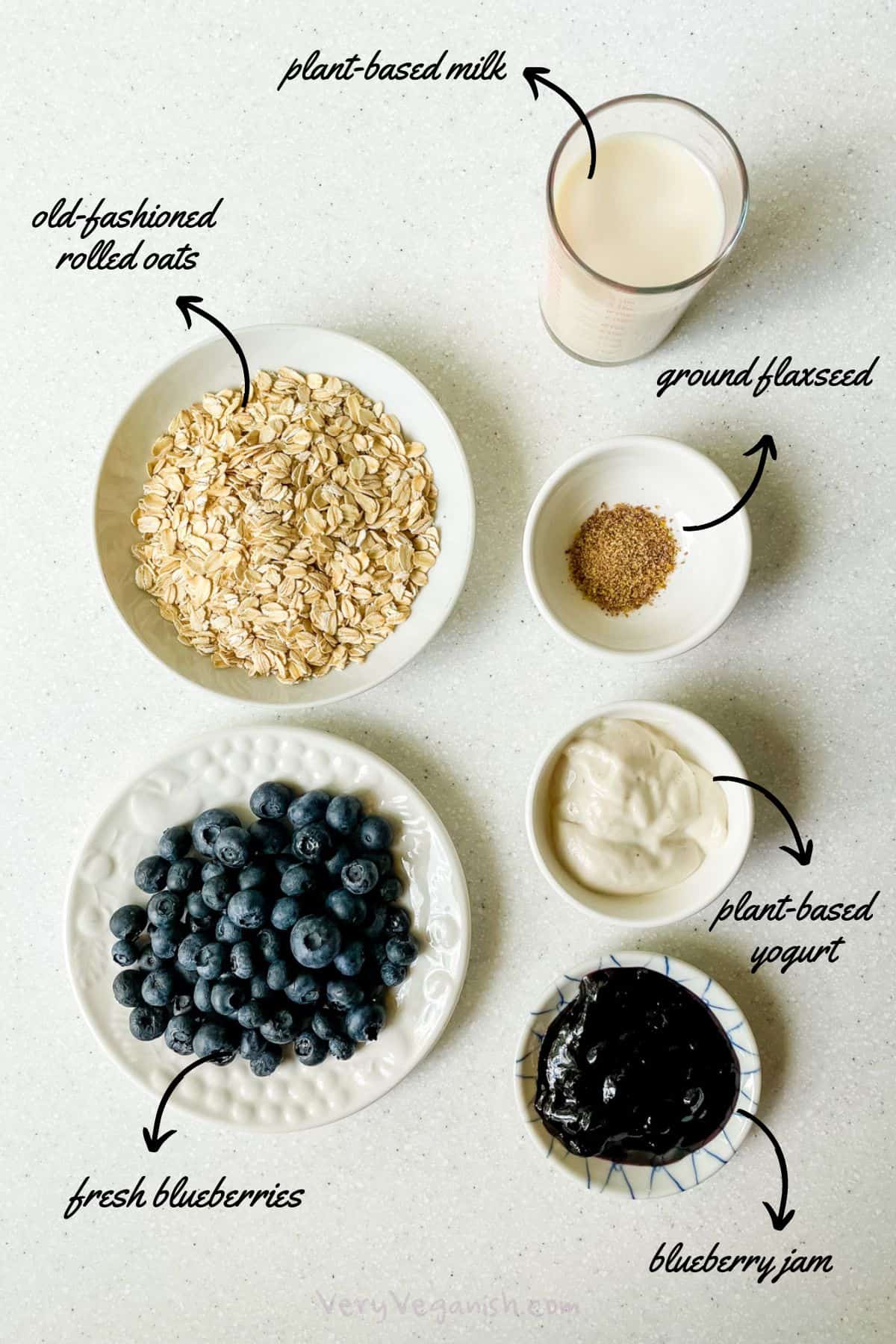 Ingredients for blueberry overnight oats with jam: rolled oats, plant-based milk, ground flax, plant-based yogurt, blueberry jam and fresh or frozen blueberries