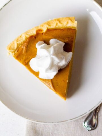 slice of vegan pumpkin pie with whipped cream on a plate