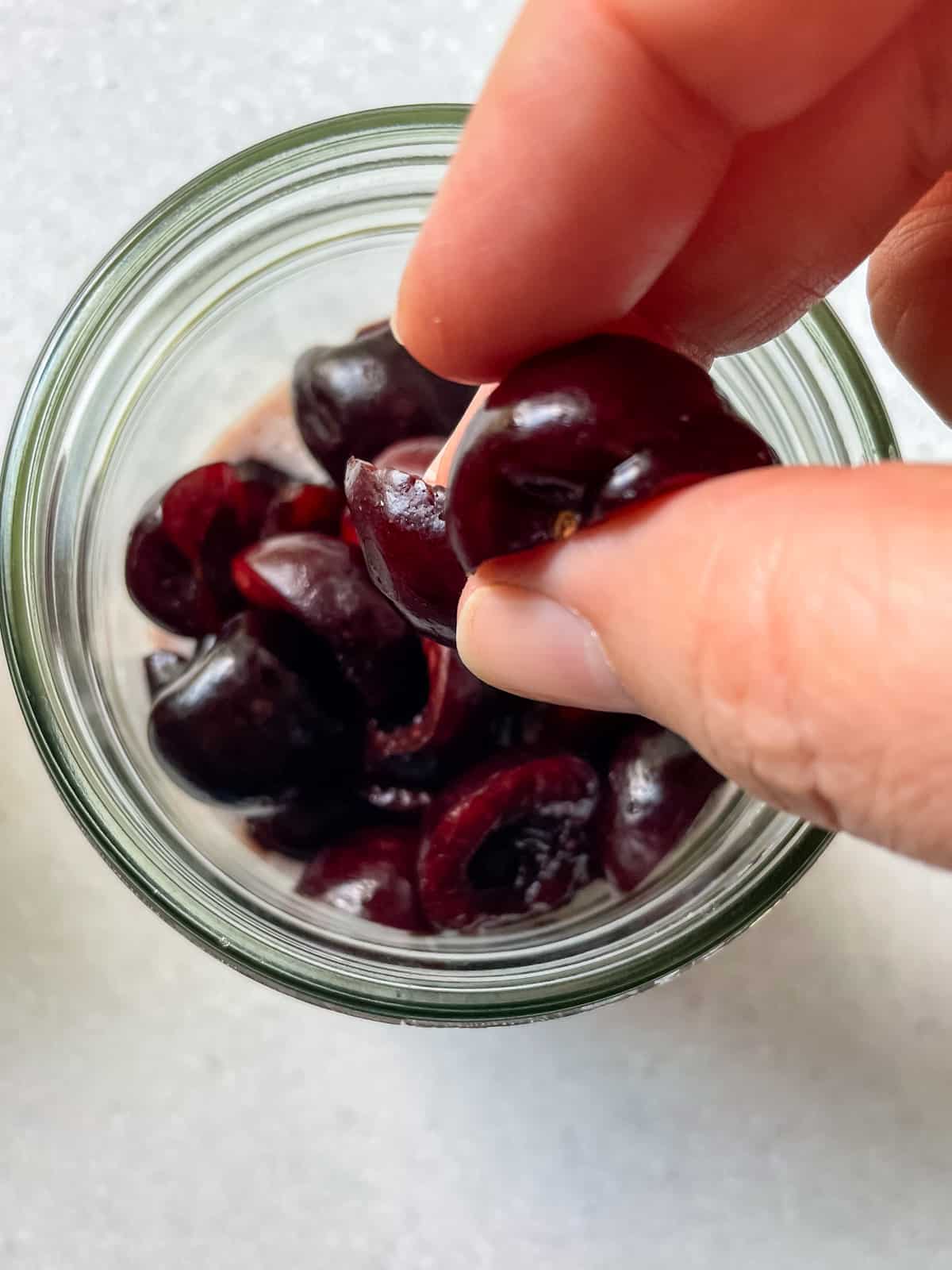 adding fresh pitted cherry halves to jar