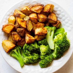 bowl of roasted potatoes with steamed broccoli
