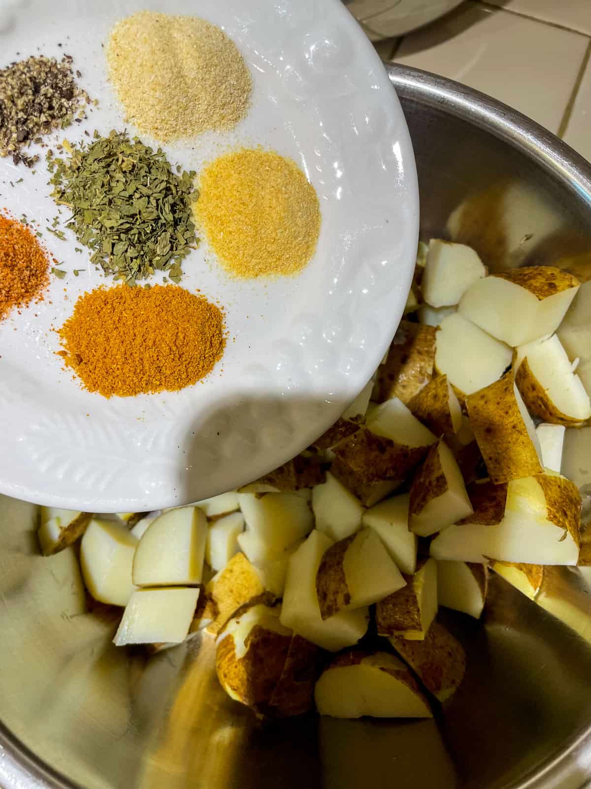 adding spices to bowl of potatoes